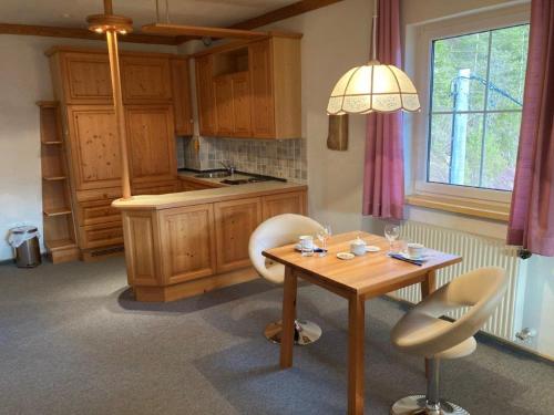 een keuken met een tafel en twee stoelen en een tafel en een raam bij Motel Brunner Apartments & Zimmer in Bad Eisenkappel