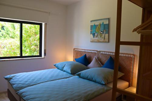 een slaapkamer met een bed met blauwe kussens en een raam bij Casa Barbara in Armação de Pêra