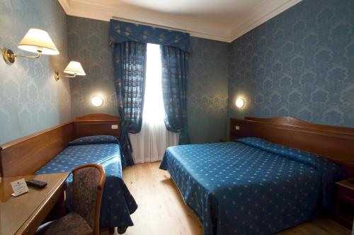 a bedroom with two beds and a desk and a window at Hotel Montecarlo in Rome