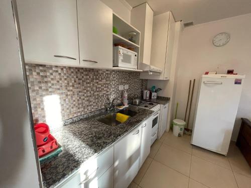 cocina con armarios blancos, fregadero y refrigerador en Departamentos Céntricos Modernos - Pagos en USD - Consultar Disponibilidad por Teléfono en Gualeguaychú