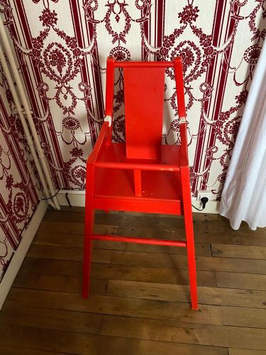 a red chair sitting in front of a wall at Grand Gîte à 25 minutes du Puy Du Fou in Montournais