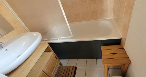 ein Badezimmer mit einer weißen Badewanne und einem Waschbecken in der Unterkunft Maisonnette 4 personnes avec piscine commune à 500 mètres de la plage - MAEL in Guidel