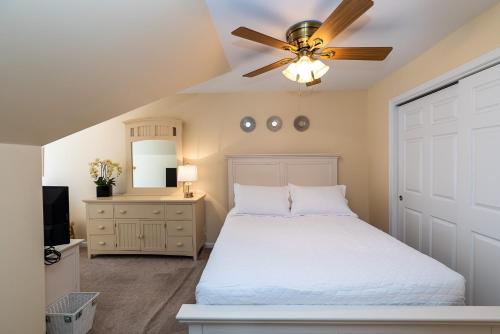 1 dormitorio con cama blanca y ventilador de techo en Ohana Hideaway, 