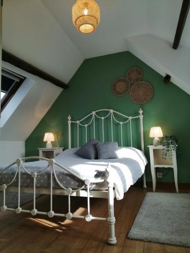 une chambre avec un lit blanc avec un mur vert dans l'établissement La Vieille Ferme, à Donnay