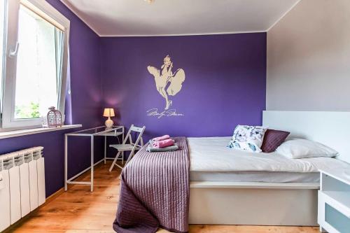 索波特的住宿－Mieszkanie przy Niepodległości 865 w Sopocie，一间卧室设有紫色的墙壁和一张带书桌的床
