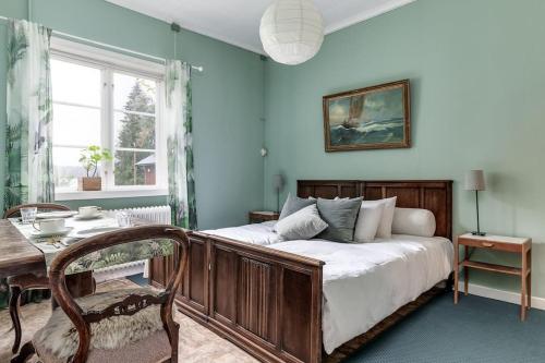 a bedroom with a bed and a table and a window at Historic lakeside villa - ski, boat, relax in nature in Sunnansjö