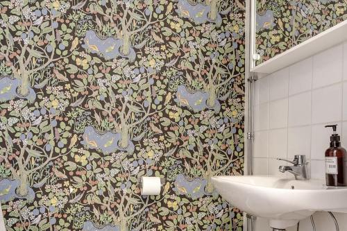 a bathroom with a sink and a floral wallpaper at Historic lakeside villa - ski, boat, relax in nature in Sunnansjö