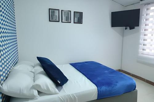 a bedroom with a bed with blue and white pillows at GURUS FR | Apartamento Central Cerca al estadio y aeropuerto in Pereira