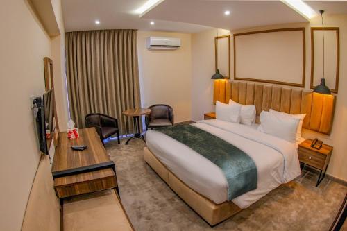 Una habitación de hotel con una cama grande y un escritorio. en POST Hotel Amman, en Amán