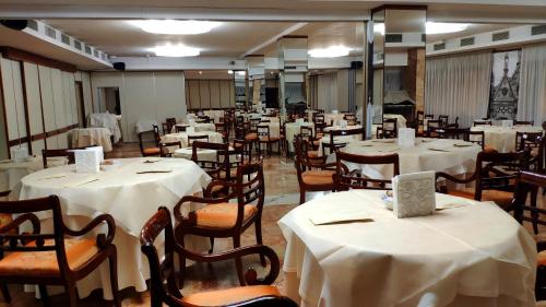 a dining room with tables and chairs with white table cloth at Grand Hotel Duomo in Pisa