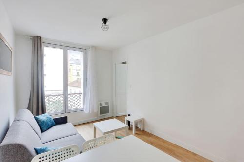 a living room with a couch and a window at Appartement Suite aux Portes de Paris in Clichy