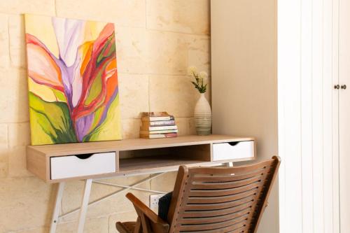 a desk with a painting on a wall with a chair at A remarkable Eco Home in Gozo in Nadur