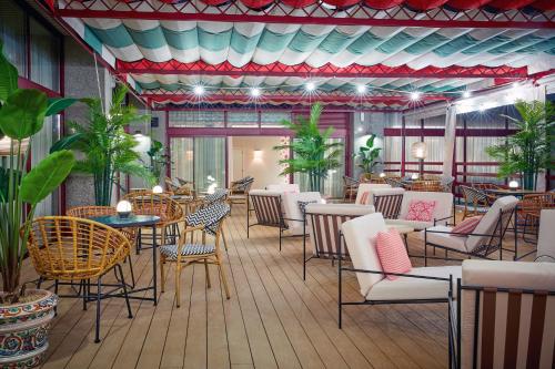 a restaurant with tables and chairs and plants at Hesperia Sevilla in Seville