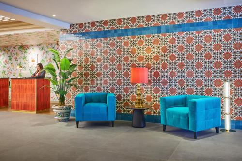 a lobby with two blue chairs and a table at Hesperia Sevilla in Seville