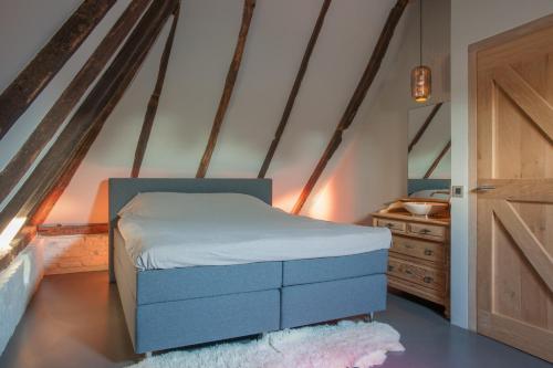 een slaapkamer met een blauw bed en een houten dressoir bij Logies Groot Okhorst in Wichmond