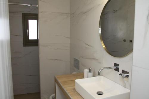 a white bathroom with a sink and a mirror at Tressos Maisons in Kimolos