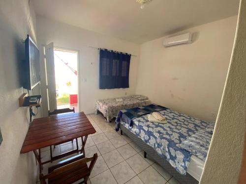 a room with two beds and a desk and a table at Pousada Brisa do Mar in Galinhos