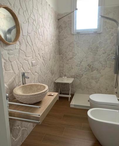 a bathroom with a bowl sink and a toilet at Villa Clemente in Marina di Lizzano