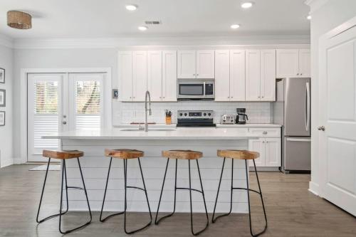 a kitchen with white cabinets and a kitchen island with stools at Ride The Wave 5 min to Beach 7 min to Dtwn in Charleston