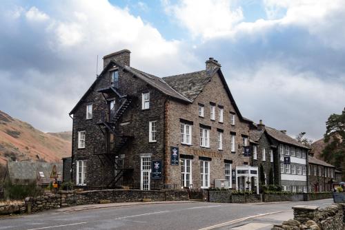 a large brick building on the side of a road at The Ullswater Inn- The Inn Collection Group in Glenridding