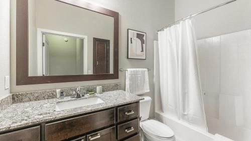 y baño con lavabo, aseo y espejo. en Landing Modern Apartment with Amazing Amenities (ID4080X59) en Minnetonka