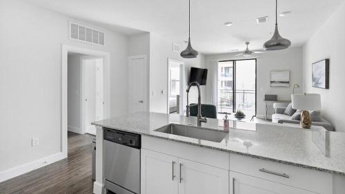 eine weiße Küche mit einem Waschbecken und ein Wohnzimmer in der Unterkunft Landing Modern Apartment with Amazing Amenities (ID9022X02) in Frisco