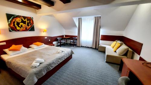 um quarto de hotel com uma cama e um sofá em Malachit Medical SPA Hotel em Karpacz