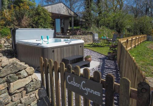a hot tub in a backyard with a fence at Caban Cynnes in Troedyraur