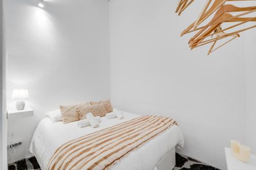 a white bedroom with a bed with a striped blanket at Casa da Junqueira - Lago do Alqueva in Campinho