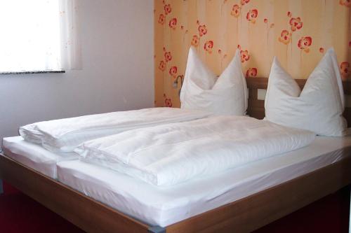 ein Bett mit weißer Bettwäsche und Kissen darauf in der Unterkunft Ferienwohnung Kottmarsdorf in Kottmarsdorf