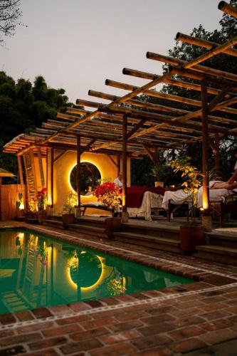a swimming pool with a pergola next to a house at El EQUIMITE HOTEL BOUTIQUE in Coatepec