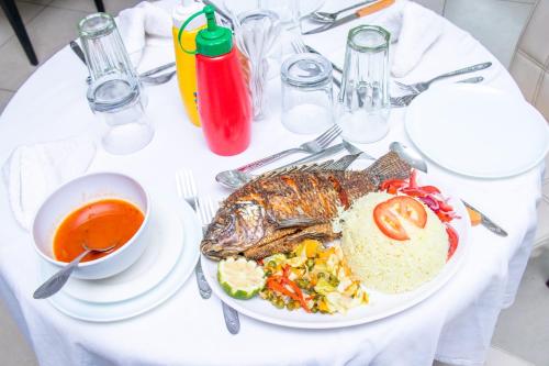 Epitome Times Hotel في نيروبي: طاولة بيضاء مع صحن من السمك وصحن من الشوربة