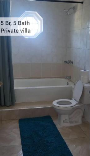 a bathroom with a toilet and a bathtub with a window at Belle Air Seaview ( 2 Bdrm -2 Bath) in Runaway Bay