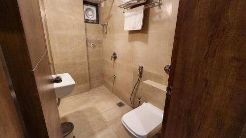 a small bathroom with a toilet and a shower at Jupiter Gold Delhi Airport in New Delhi
