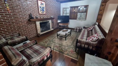 a living room with couches and a brick wall at CASA EM MONTE VERDE-MG ACOMODA 15 PESSOAS in Monte Verde