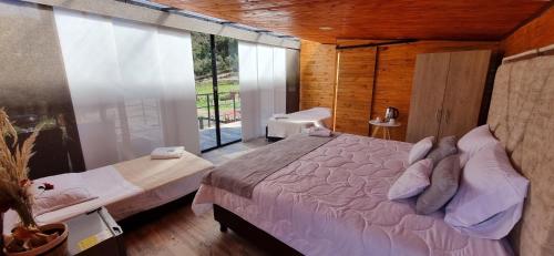 a bedroom with a bed and a large window at NaturaLove Glamping Mongui in Monguí
