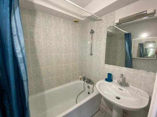 une salle de bain avec un lavabo, une baignoire et un miroir dans l'établissement Maisonnette 4 pers - Piscine commune - plage à 500 m- ARGANE, à Guidel-Plage