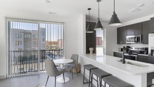 een keuken met een wit aanrecht en een tafel en stoelen bij Landing - Modern Apartment with Amazing Amenities (ID1398X195) in Richmond