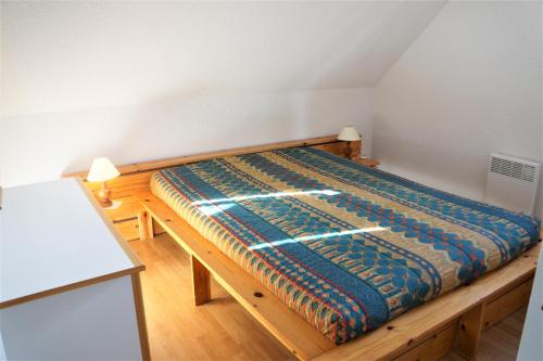 une chambre avec un lit en bois dans une pièce dans l'établissement Maisonnette 4 pers - Piscine commune - plage à 500 m- ARGANE, à Guidel-Plage