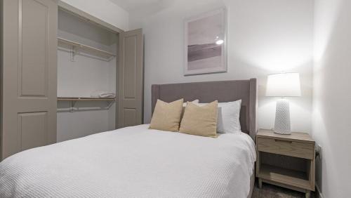 um quarto com uma cama branca e um candeeiro numa mesa de cabeceira em Landing - Modern Apartment with Amazing Amenities (ID1403X401) em Houston