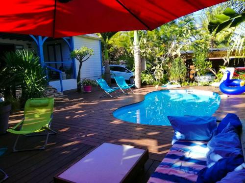 een patio met een zwembad, stoelen en een parasol bij Villa d'une chambre avec piscine privee terrasse et wifi a La Riviere Saint Louis a 8 km de la plage in Saint-Louis