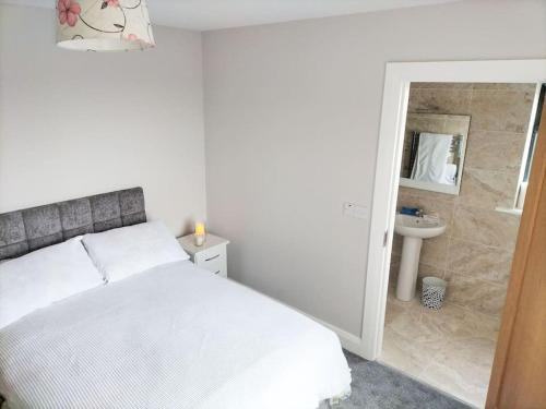 a white bedroom with a bed and a sink at Lake view Dunfanaghy in Dunfanaghy