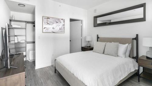 a white bedroom with a bed and a mirror at Landing - Modern Apartment with Amazing Amenities (ID1401X727) in Fort Lauderdale