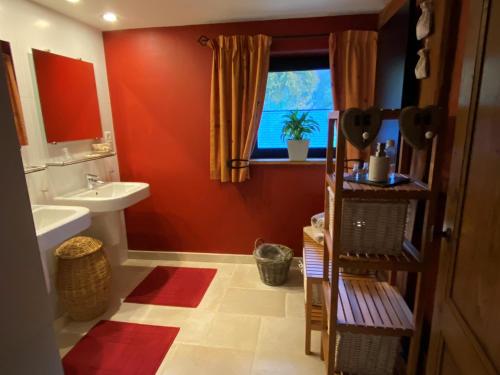 a bathroom with red walls and a sink and a window at Chambre d'hôtes - Le Refuge de la Vallée in Érezée