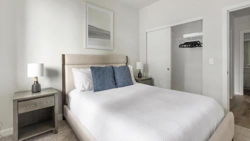 a white bed with blue pillows in a bedroom at Landing - Modern Apartment with Amazing Amenities (ID1403X373) in Portland