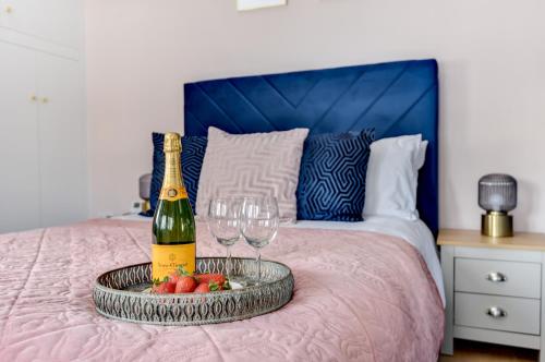 Una botella de champán y dos copas en una cama. en Modern 1 bed close to town and station, en Worthing