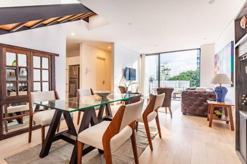 a dining room with a glass table and chairs at Penthouse, terraza privada y estacionamiento in Mexico City