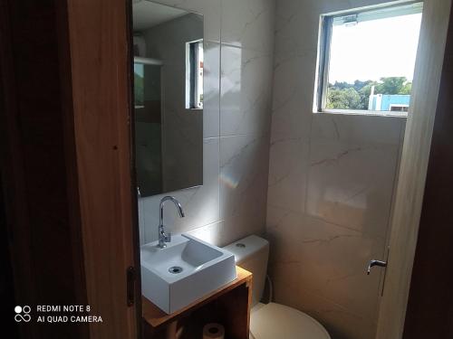 baño con lavabo y aseo y ventana en Casa Container Amarela, en Bagé