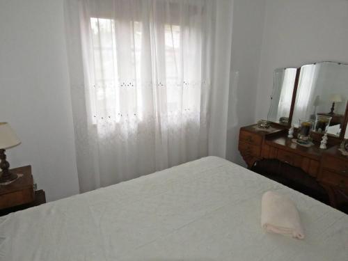1 dormitorio con cama blanca, espejo y ventana en One bedroom house with terrace and wifi at Miranda do Corvo, en Vale de Colmeias