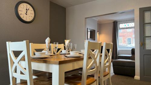 a dining room table with chairs and a clock on the wall at The Deeside in Buckley